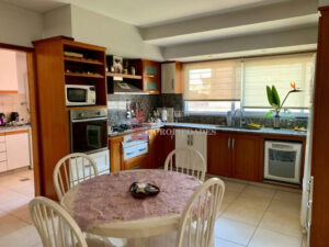 Cocina amplia muy iluminada con grandes ventanas, mesada en mármol y muebles de madera. Venta casa de categoría en Ezpeleta.