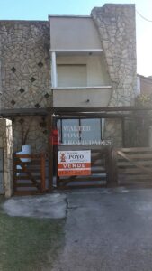 Frente en piedra con tranquera de madera rústica. Casa en Santa Clara del Mar.